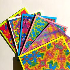 five brightly colored papers are stacked on top of each other in a square shape with different patterns