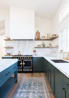 a kitchen with green cabinets and an area rug in front of the stove top oven