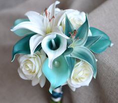 a bridal bouquet with white roses and blue calla lilies on a couch