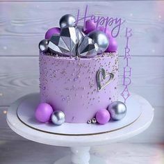 a birthday cake with purple frosting and silver decorations