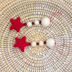 two red and white felt stars are on a wicker basket with twine beads