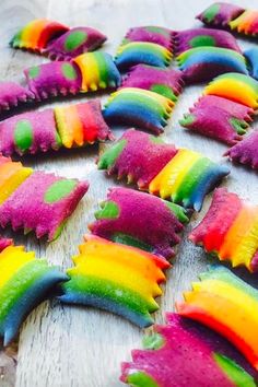 rainbow cookies are arranged on a wooden table