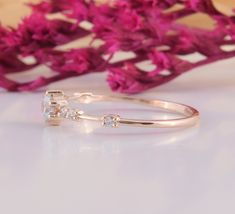 a close up of a ring on a table with pink flowers in the back ground