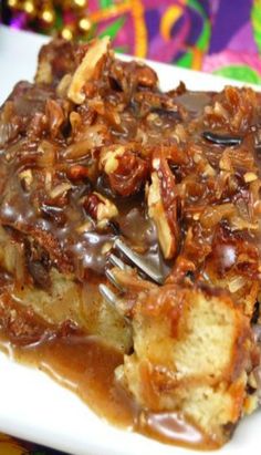 a close up of a piece of cake on a plate with chocolate sauce and pecans