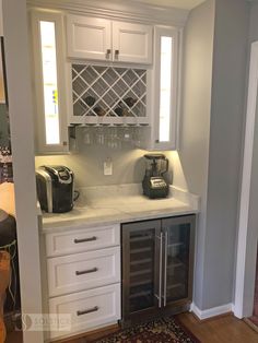 a kitchen with white cabinets and wine racks on the counter top, along with a red area rug