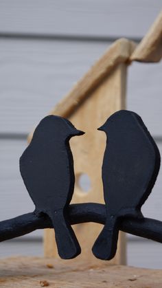 two black birds sitting on top of a wooden chair