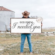 a man holding a sign that says god knew i needed you in front of a grain silo