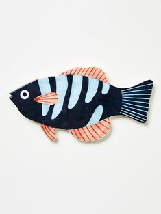 a black and white fish with orange stripes on it's body, sitting on a white surface