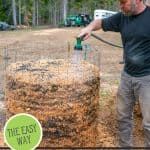 a man standing next to a hay bale holding a green object in his hand