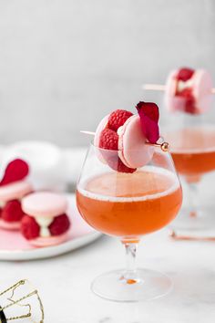 two glasses filled with liquid and garnished with raspberries