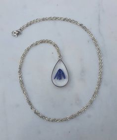 This listing is for a real bluebell stem handpicked and pressed from my garden containing 2 flower heads.  This is set in resin inside a tear drop shaped silver effect bezel pendant on a 24" silver plated chain.This necklace is so beautiful and one of a kind. It would make the perfect gift for someone special.  Please note there are tiny bubbles in the resin as you can see in the photos.Please visit my shop to see all the other types of pressed flower necklaces for sale. Minimalist Silver Jewelry With Pressed Flowers, Blue Sterling Silver Birth Flower Jewelry, Blue Sterling Silver Jewelry With Birth Flower, Silver Jewelry With Pressed Flowers For Mother's Day, Teardrop Sterling Silver Keepsake Jewelry, Sterling Silver Teardrop Keepsake Jewelry, Teardrop Jewelry With Pressed Flowers, Silver Pressed Flowers Jewelry For Memorial, Silver Pressed Flowers Memorial Jewelry