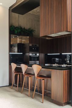 three wooden chairs sitting in front of a kitchen counter