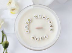 a candle with the words you were made here spelled in small letters on it next to flowers