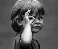 black and white photograph of a young boy covering his eyes