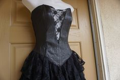 "Vintage size small black dress with leather sweetheart bodice and ruffle lace layered skirt. Zips up the back. In good vintage condition but the puller on the zipper need to be reconnected somehow - see last photo. Measurements taken across front laid flat 16\" across front armpit to armpit 12.5\" across front of waist -doubles to 25\" 19\" across front of hips 26\" length armpit to bottom" Black Corset With Lace Bodice And Fitted Bodice, Black Fitted Corset Dress With Ruffles, Vintage Black Lace Corset, Black Overbust Corset Dress With Lined Bodice, Gothic Strapless Corset Dress With Ruffles, Black Corset Dress With Lace Trim For Formal Occasions, Black Strapless Corset With Ruffles, Elegant Black Corset With Ruffles, Black Formal Corset Dress With Lace Trim