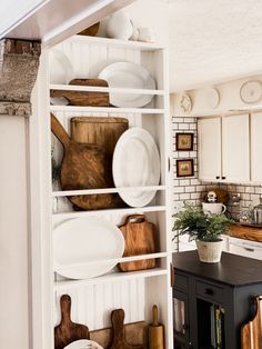 a kitchen filled with lots of white dishes and wooden utensils on top of shelves