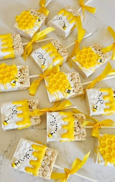 honeycomb cake pops are decorated with yellow ribbon and bees on them, sitting on a marble countertop