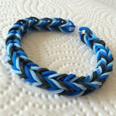 a blue and black braided bracelet sitting on top of a white surface