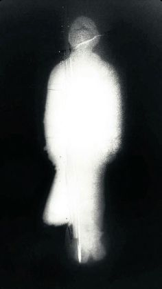 the shadow of a man in a hat is seen through a glass window with light coming from behind it