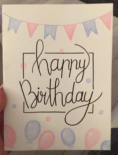 a hand holding up a birthday card with the words happy birthday written in black ink