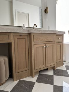 a bathroom with checkered floor and wooden cabinets