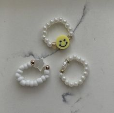 three beaded bracelets with smiley face charms on them sitting on a marble surface