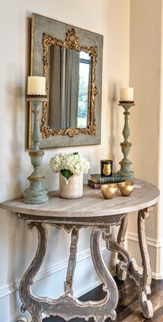 an ornate console table with candles and flowers on it in front of a large mirror