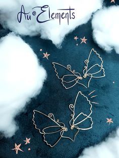 two angel brooches sitting on top of a cloud filled sky with stars in the background