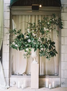 a vase filled with white flowers sitting on top of a table next to a window