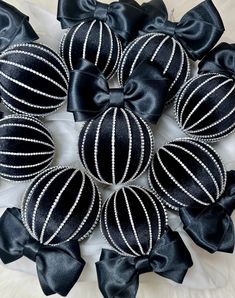 several black and white ornaments are arranged in a circle on a cloth surface with bows