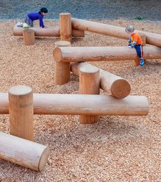 two children playing in a play area made out of logs