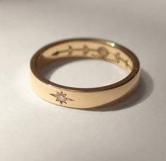 a close up of a wedding ring on a white surface with the word love written in gold