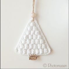 a white crocheted christmas tree ornament hanging from a string on a wall