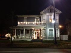 a house is decorated with christmas lights and garlands on the front porch at night