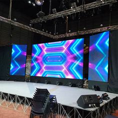 the stage is set up for an event with three large screens on it and several chairs in front