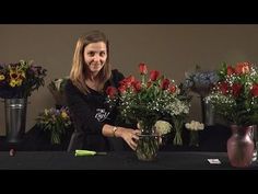 a woman standing behind a table with vases filled with flowers