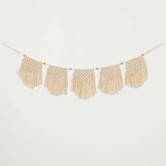 three tasselled fringes hanging from a string on a white wall in front of a