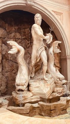 a statue of a man with two fish in front of a stone wall and archway