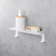 a white shelf with a brush and soap dispenser sitting on top of it