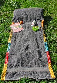 a blanket and some food on the ground in the grass with an orange, yellow and blue striped edge