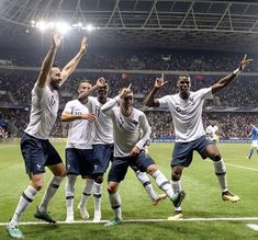 a group of men on a field playing soccer with their hands up in the air