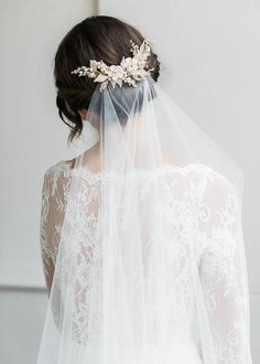 a woman wearing a veil with flowers on it's head is seen from behind