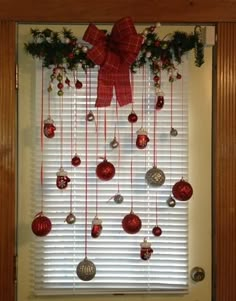 christmas decorations hanging on the window sill with red bows and baubles attached to it