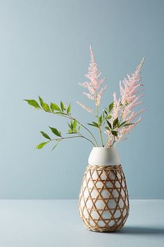 a vase with some flowers in it on a blue tableclothed surface against a gray wall