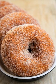 three sugar covered donuts in a white bowl