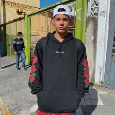 a young man wearing a black hoodie with red roses on the sleeve and sleeves