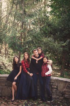 a family poses for a photo in front of some trees and rocks with their arms around each other