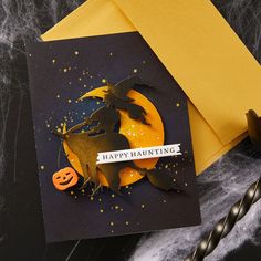 a halloween card with an orange pumpkin and witch on it, next to a yellow envelope