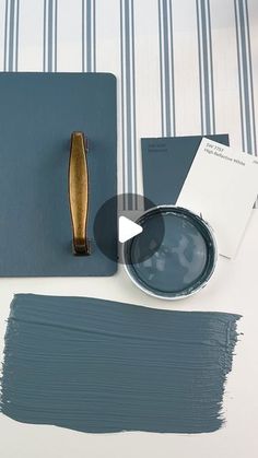 some blue and white paint on a table with a gold brush next to it's holder