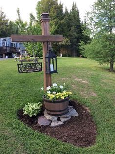 a wooden cross sitting on top of a lush green field next to a potted plant